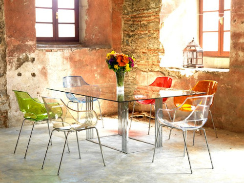 Разноцветные прозрачные стулья вокруг стеклянного стола