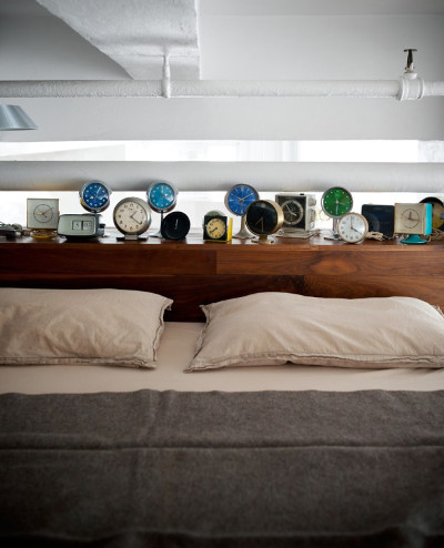 часы различных форм и размеров у изголовья кровати